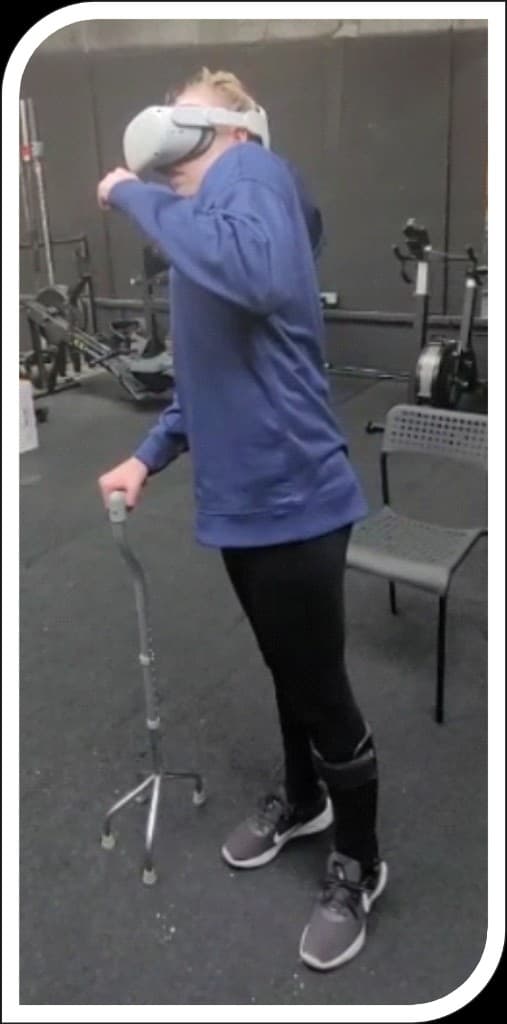 Skyla standing with VR headset and walking cane during rehabilitation